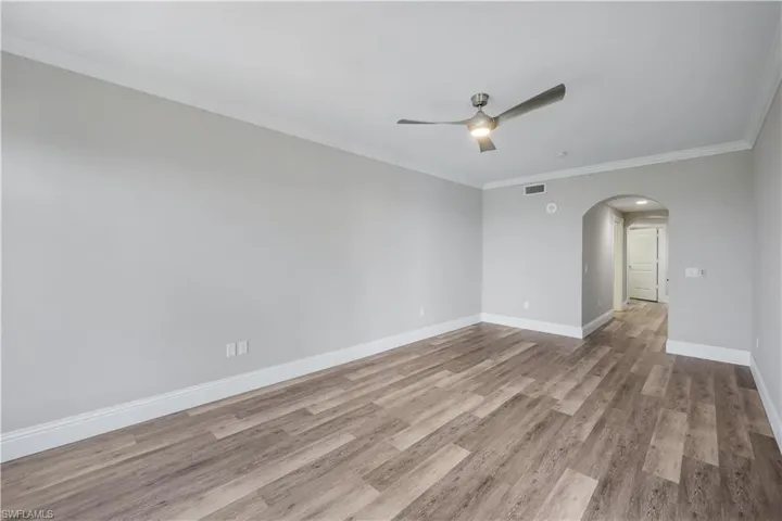 Spacious primary suite with waterfront views featuring wood-finish flooring, a contemporary ceiling fan, and crown molding