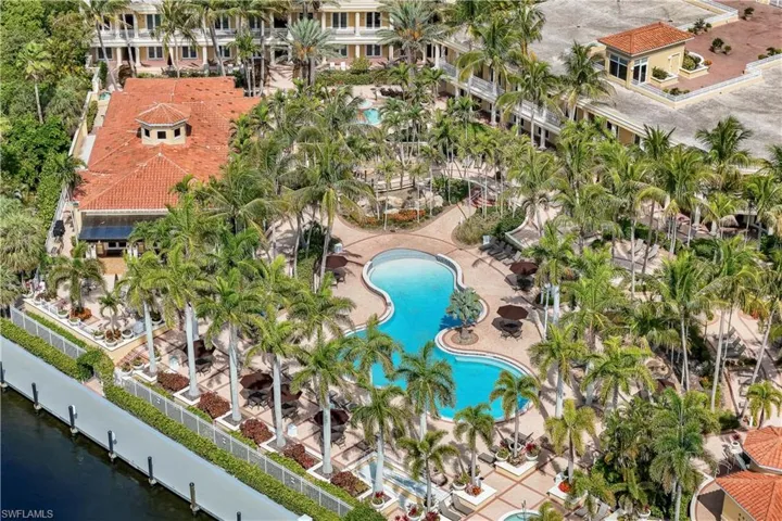 Expansive resort-style grounds featuring a large freeform swimming pool, extensive palm tree landscaping, and paved walkways