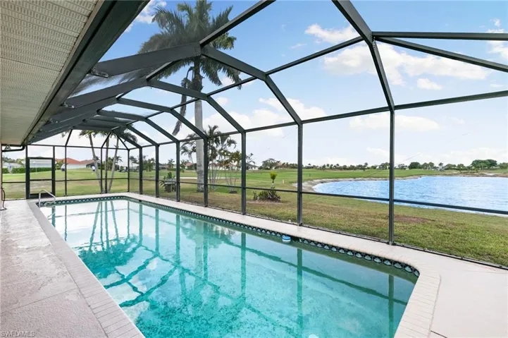 Swimming pool with a yard, a sunroom, glass enclosure, and a water view