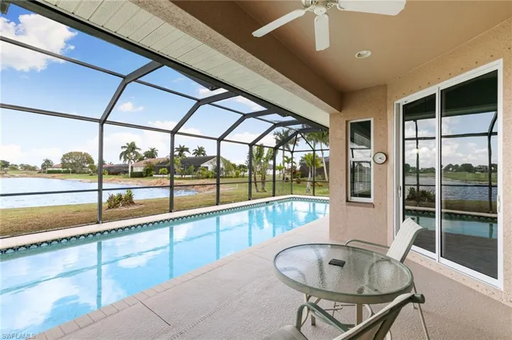 Swimming pool with a sunroom, a patio area, a lanai, a water view, and a yard
