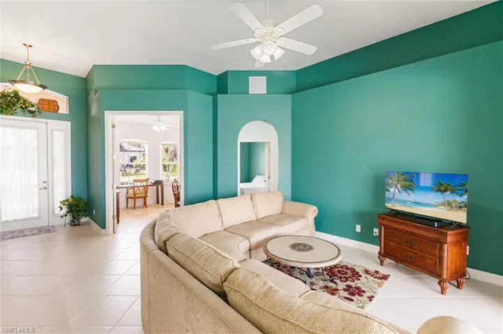 Living area featuring a ceiling fan, light tile patterned floors, and arched walkways