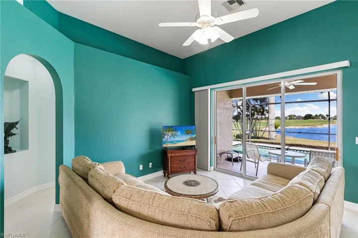 Living area with ceiling fan, arched walkways, and light tile patterned floors