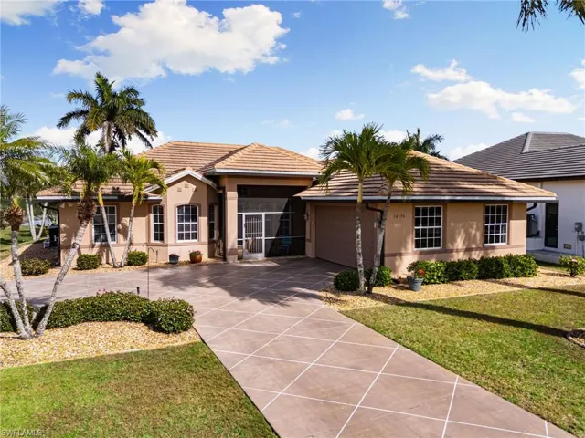 View of front of property with stucco siding, a front yard, driveway, a garage, and a tile roof