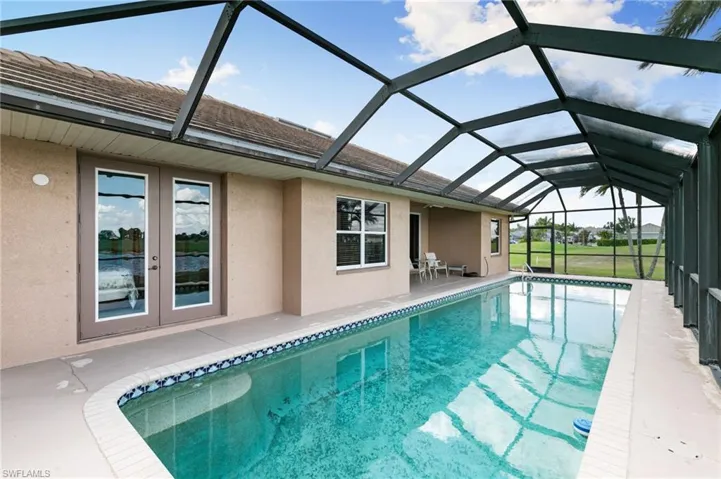 Swimming pool featuring a sunroom, a patio, french doors, and glass enclosure