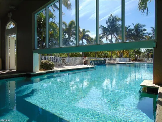 “Resort-style pool with rare indoor-outdoor transition — swim through sunlit glass walls into a lush tropical escape.”