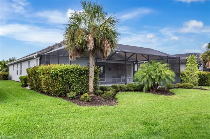 Back of property with a lawn, stucco siding, and a lanai
