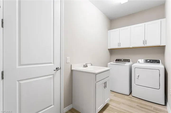 Washroom featuring independent washer and dryer, light wood finished floors, and cabinet space