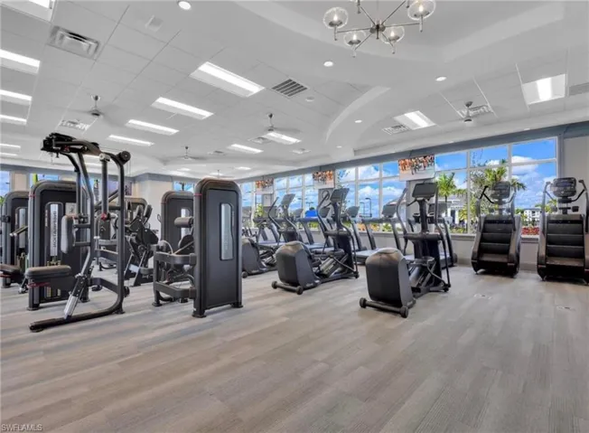 Workout area featuring carpet floors, healthy amount of natural light, a chandelier, and a paneled ceiling