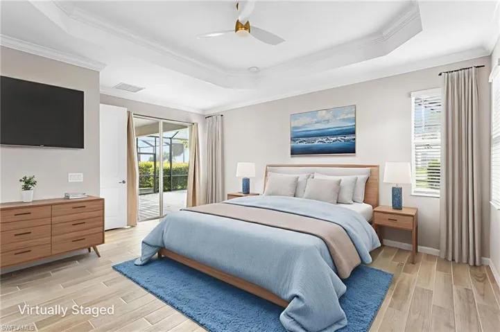 Bedroom with a raised ceiling, access to exterior, light wood-style flooring, ornamental molding, and ceiling fan