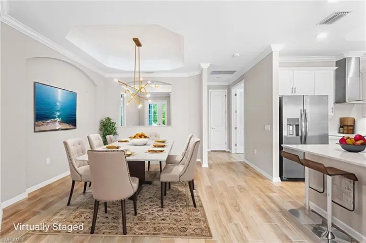 Dining space with a chandelier, light wood finished floors, ornamental molding, a raised ceiling, and recessed lighting