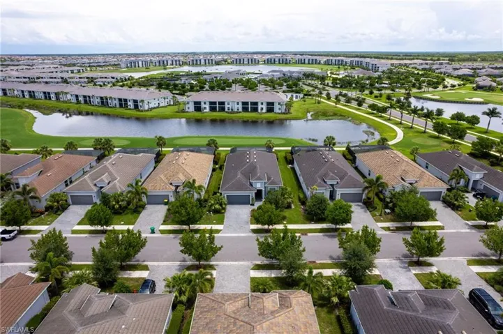 Aerial perspective of suburban area featuring a local golf course and a nearby body of water