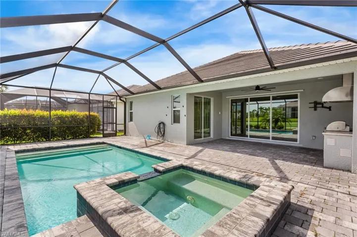 View of swimming pool featuring ceiling fan, a patio, a pool with connected hot tub, and an outdoor kitchen
