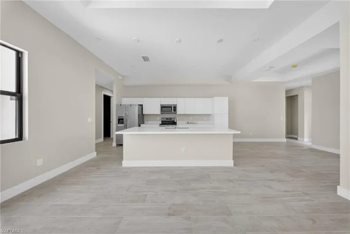 Open-concept living area with plank-style flooring, a large kitchen island, and recessed lighting