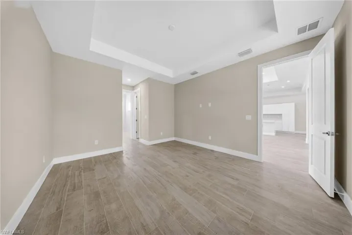 Spacious room featuring wood-finish flooring, neutral wall tones, and crown molding