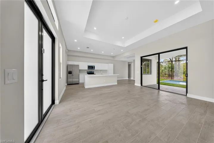 Spacious open-concept living area featuring wood-finish flooring, recessed lighting, and a tray ceiling