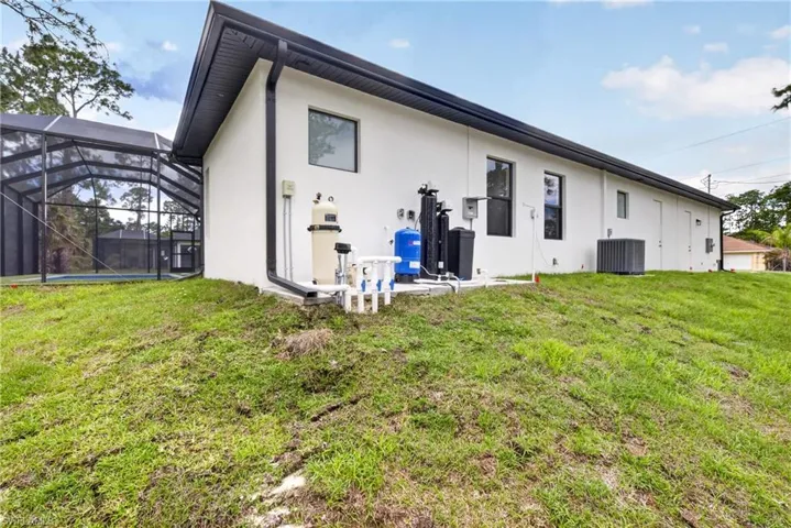 Rear exterior showcasing a screened pool enclosure and white stucco siding