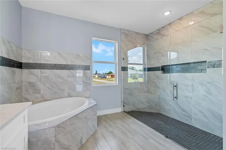 Bathroom with a bath, a shower stall, and baseboards