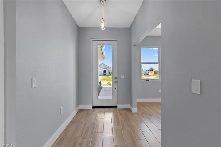 Foyer featuring a textured wall, light wood-style floors, and baseboards