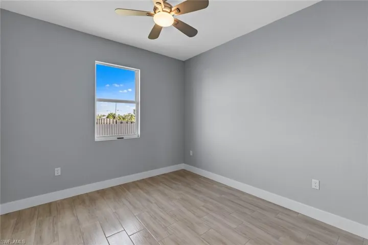 Empty room featuring light wood finished floors, ceiling fan, and baseboards