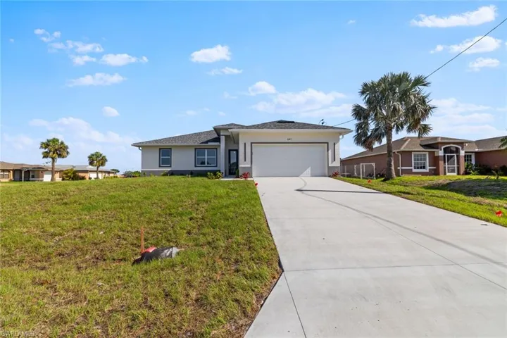 Ranch-style house featuring a garage, driveway, stucco siding, and a front lawn