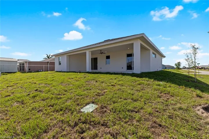 Back of house featuring a yard, stucco siding, and a ceiling fan