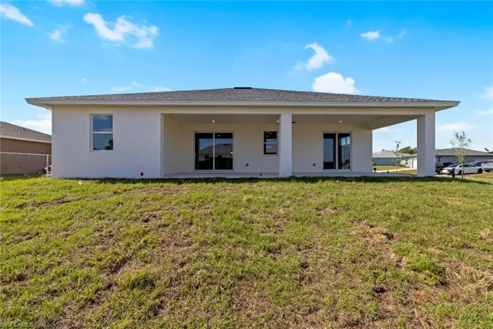 Rear view of property with stucco siding and a lawn