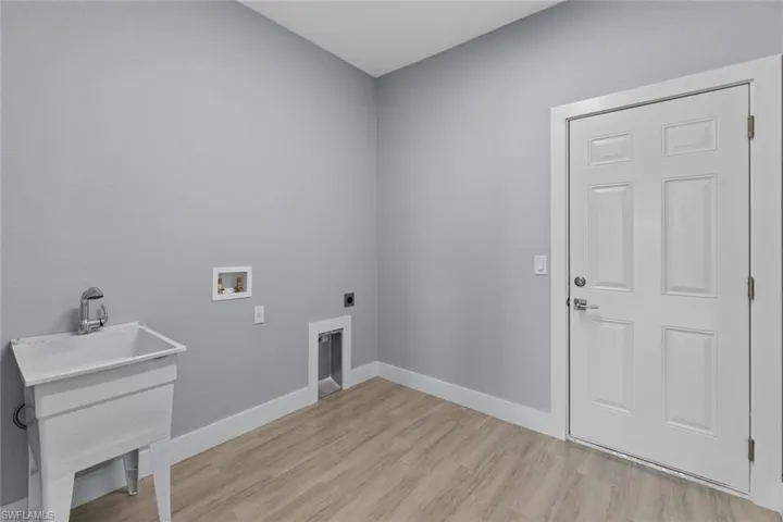 Clothes washing area featuring laundry area, hookup for a washing machine, electric dryer hookup, light wood-type flooring, and baseboards