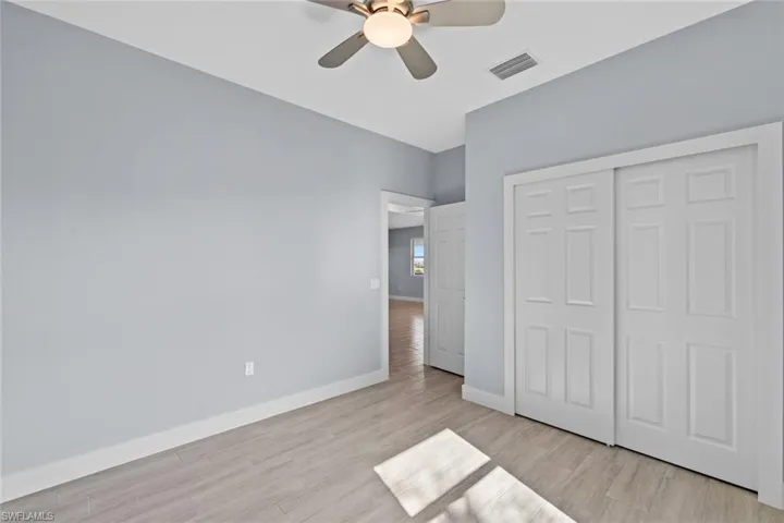 Unfurnished bedroom featuring baseboards, a closet, light wood-style floors, visible vents, and ceiling fan