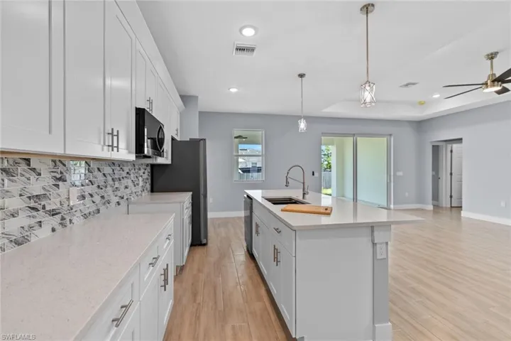 Kitchen featuring tasteful backsplash, visible vents, a sink, stainless steel appliances, and a raised ceiling