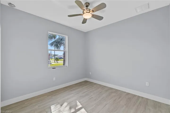 Empty room featuring ceiling fan, visible vents, baseboards, and wood finished floors