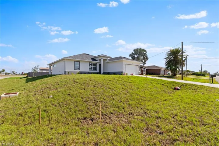 View of front of house featuring a garage, stucco siding, concrete driveway, and a front lawn
