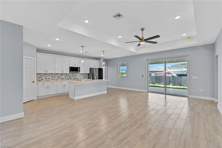 Kitchen with open floor plan, backsplash, visible vents, a tray ceiling, and appliances with stainless steel finishes