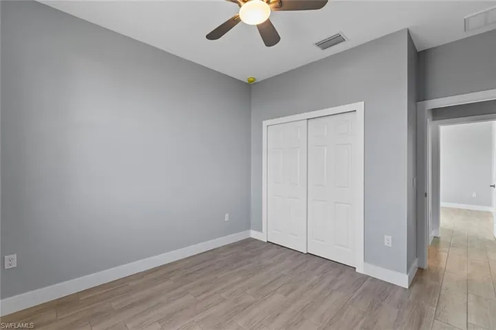 Unfurnished bedroom featuring visible vents, baseboards, a closet, and wood finished floors