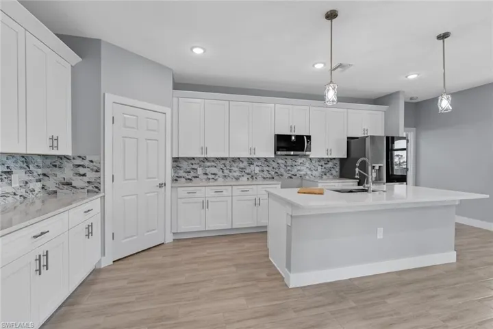 Kitchen featuring white cabinetry, decorative light fixtures, visible vents, stainless steel appliances, and a sink