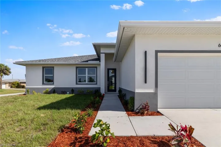 View of front of property with a front yard, an attached garage, concrete driveway, stucco siding, and roof with shingles