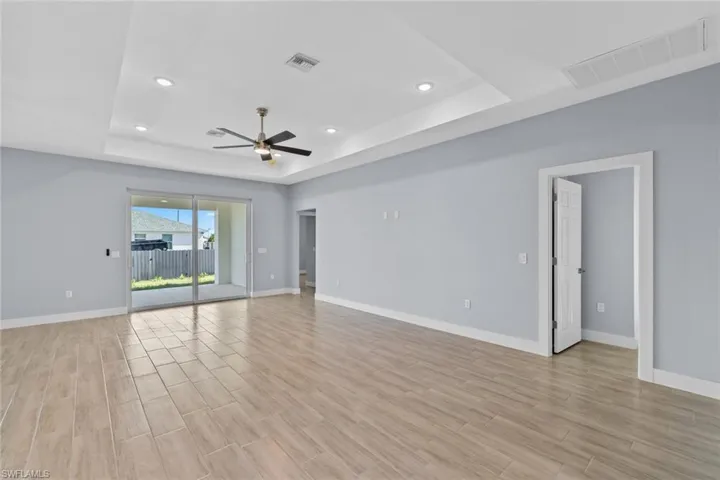 Spare room with visible vents, baseboards, a raised ceiling, a ceiling fan, and light wood-style floors