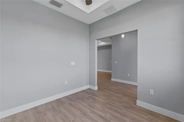 Unfurnished room featuring ceiling fan, visible vents, baseboards, and wood finished floors