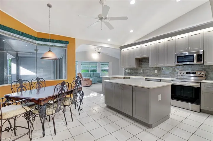 Kitchen featuring gray cabinets, stainless steel appliances, hanging light fixtures, and vaulted ceiling