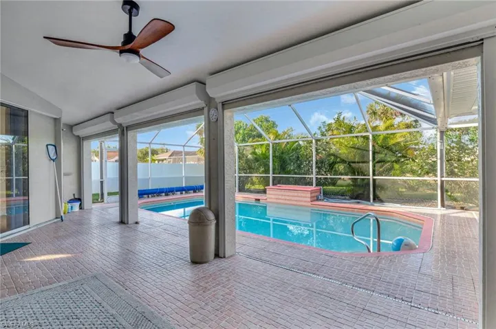 View of pool with ceiling fan, a patio area, and glass enclosure