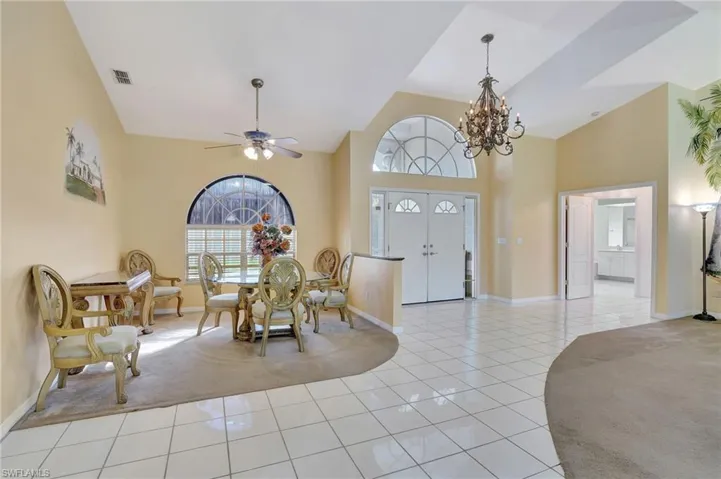 Tiled foyer entrance with a towering ceiling and ceiling fan with notable chandelier