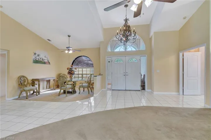 Carpeted foyer with ceiling fan with notable chandelier and a towering ceiling