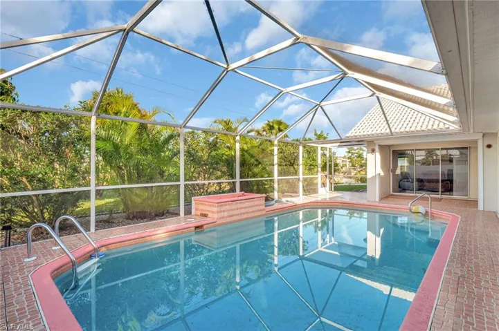 View of pool with glass enclosure and a patio area