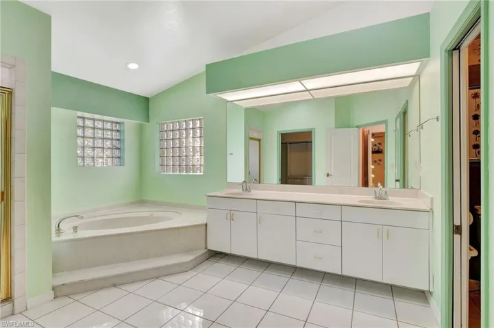 Bathroom with shower with separate bathtub, vanity, tile patterned floors, and lofted ceiling