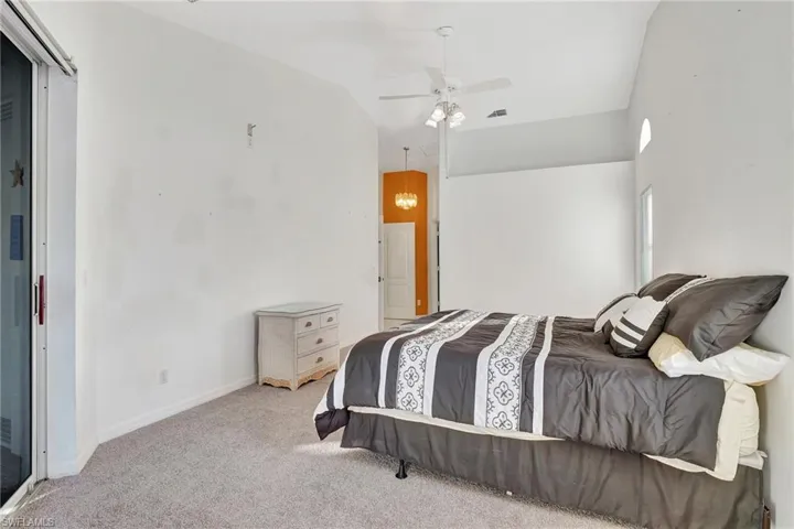 Carpeted bedroom featuring ceiling fan and vaulted ceiling