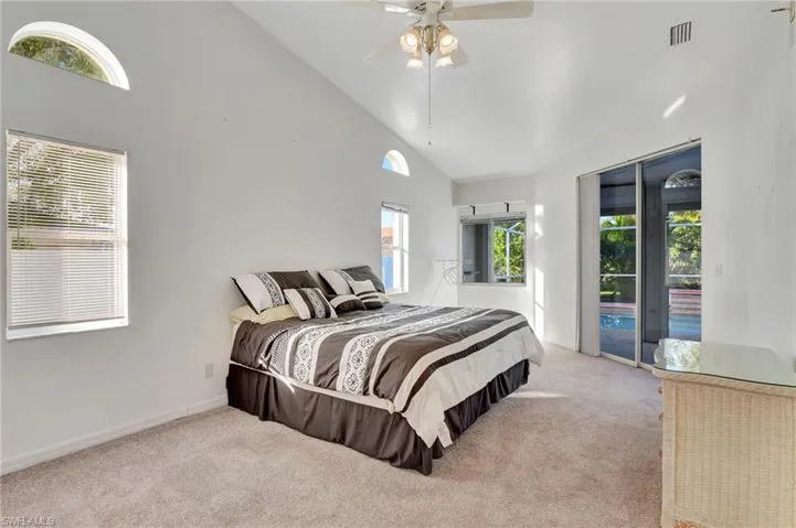 Carpeted bedroom with access to exterior, high vaulted ceiling, and ceiling fan