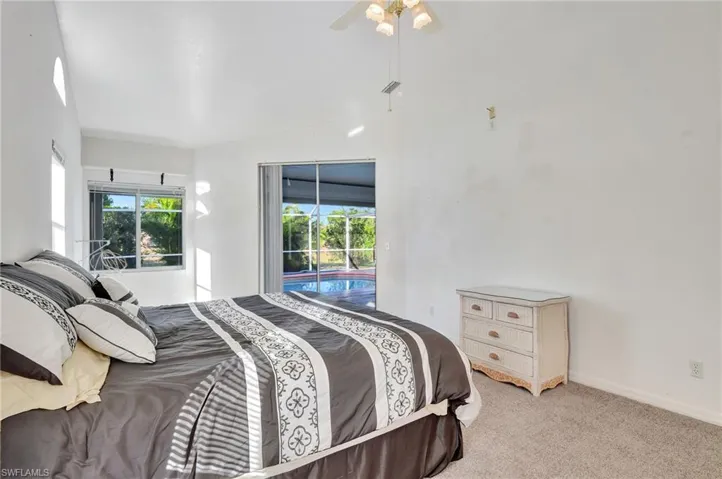 Bedroom with ceiling fan, light colored carpet, and lofted ceiling