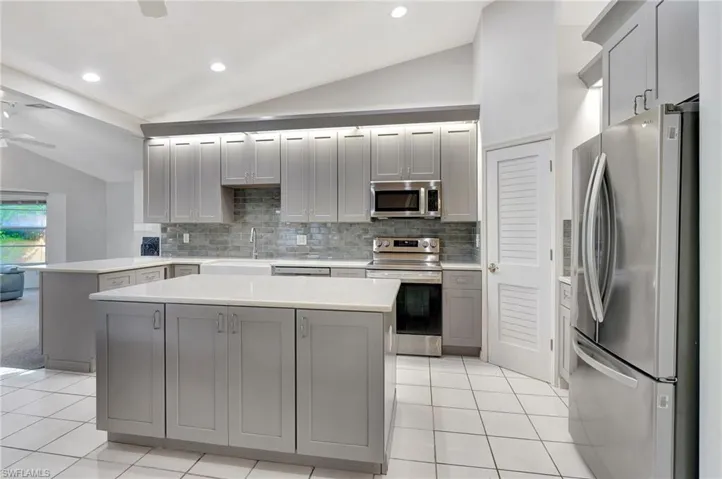 Kitchen featuring backsplash, a kitchen island, lofted ceiling, and appliances with stainless steel finishes