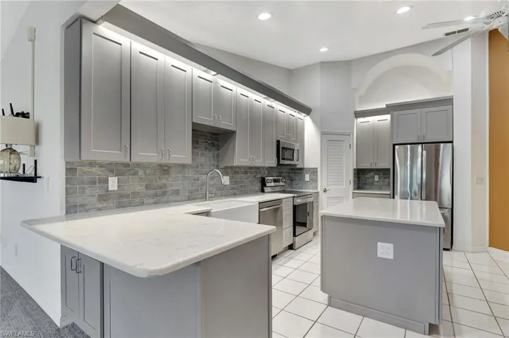 Kitchen with ceiling fan, light tile patterned floors, gray cabinets, a kitchen island, and appliances with stainless steel finishes