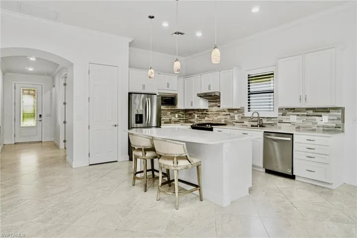 Oversized marble-look tile flooring laid on the diagonal, coffered ceilings in the living room, and abundant natural lightthroughout.