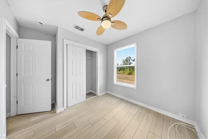 Unfurnished bedroom featuring light wood finished floors, a closet, and ceiling fan